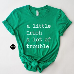 May include: A green t-shirt with white text that reads "a little Irish a lot of trouble".
