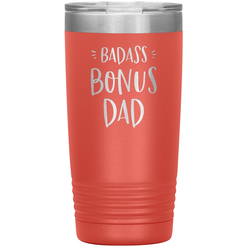 May include: A coral-colored stainless steel tumbler with a white inscription that reads "Badass Bonus Dad".