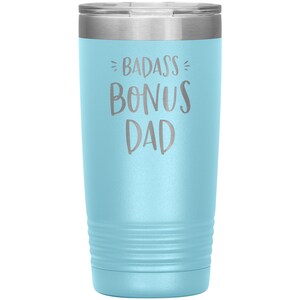 May include: A light blue stainless steel tumbler with a silver lid. The tumbler has the text "BADASS BONUS DAD" engraved on the front.