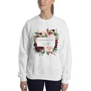 Peut inclure: Sweat-shirt blanc avec un motif floral et le texte "GENEALOGY IT'S ALL ABOUT THE ROOTS" dans un cadre dor&eacute;.