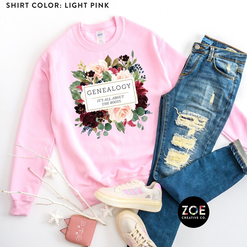 Peut inclure: Sweat-shirt rose p&acirc;le avec un motif floral et le texte "GENEALOGY IT'S ALL ABOUT THE ROOTS".