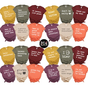 May include: A selection of colourful t-shirts, each printed with a different German-themed slogan in white text. The phrases include references to beer, pretzels, and German culture. The shirts are displayed in rows, offering a range of colours and designs.