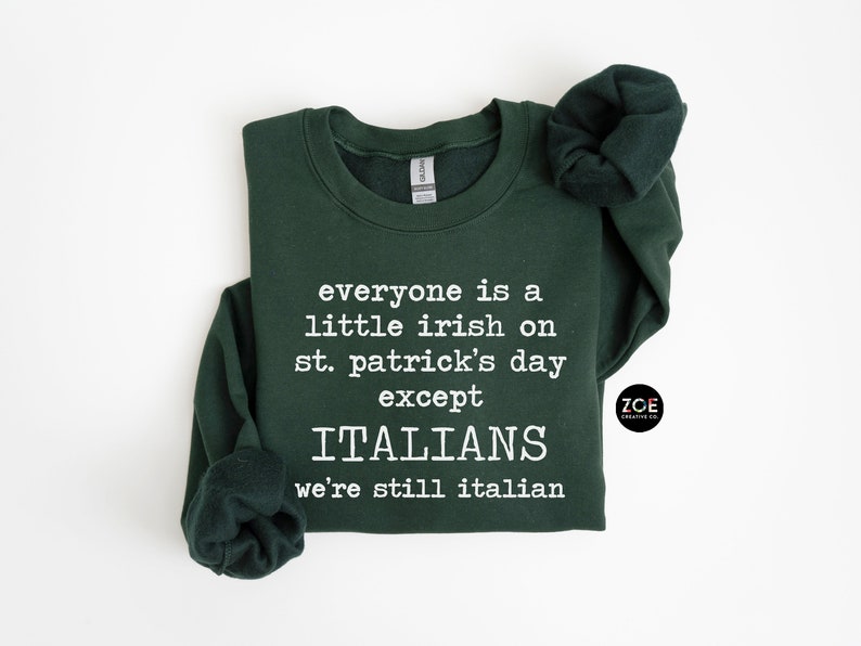 May include: Dark green sweatshirt with white text: "everyone is a little irish on st. patrick's day except ITALIANS we're still italian." Features a crew neck and long sleeves. The Zoe Creative Co. logo is on the right.
