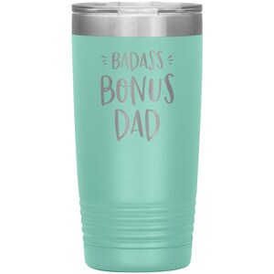 May include: A teal stainless steel tumbler with a silver lid. The tumbler has the text "BADASS BONUS DAD" engraved on the front.