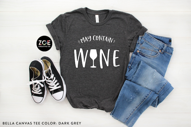 K&ouml;nnte beinhalten: Ein dunkelgraues T-Shirt mit dem Text "May Contain Wine" und einer in Wei&szlig; gedruckten Grafik eines Weinglases.