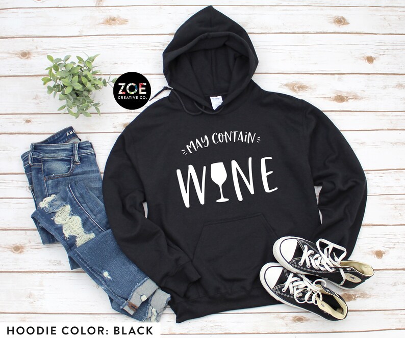 K&ouml;nnte beinhalten: Schwarzer Hoodie mit wei&szlig;em Text "May Contain Wine" und einer Weinglasgrafik.