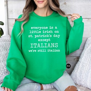 May include: A bright green sweatshirt with white text that reads "everyone is a little irish on st. patrick's day except ITALIANS we're still italian". The sweatshirt is a crew neck style.