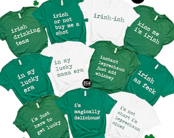 May include: A collection of green and white t-shirts with various St. Patrick's Day themed sayings. The sayings include "irish drinking team", "irish or not buy me a shot", "irish-ish", "kiss me i'm irish", "in my lucky era", "in my lucky mama era", "instant leprechaun just add whiskey", "irish as feck", "i'm just here to get lucky", "i'm magically delicious!" and "i'm not short i'm leprechaun sized".