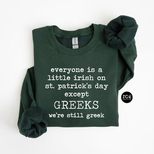 May include: A dark green sweatshirt with the text "everyone is a little irish on st. patrick's day except GREEKS we're still greek" printed in white.