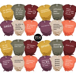 May include: A selection of colourful t-shirts with Oktoberfest slogans and designs. The shirts display phrases such as "Prost!", "Oktoberfest", and "Pretzel Squad". The Zoe Creative Co. logo is visible on the shirts.