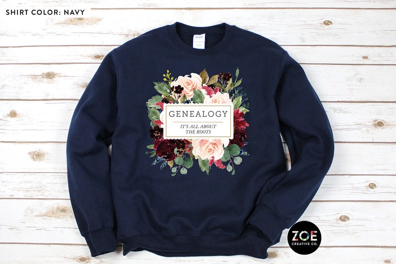 Peut inclure: Sweat-shirt bleu marine avec un motif floral et le texte "Genealogy It's all about the roots".