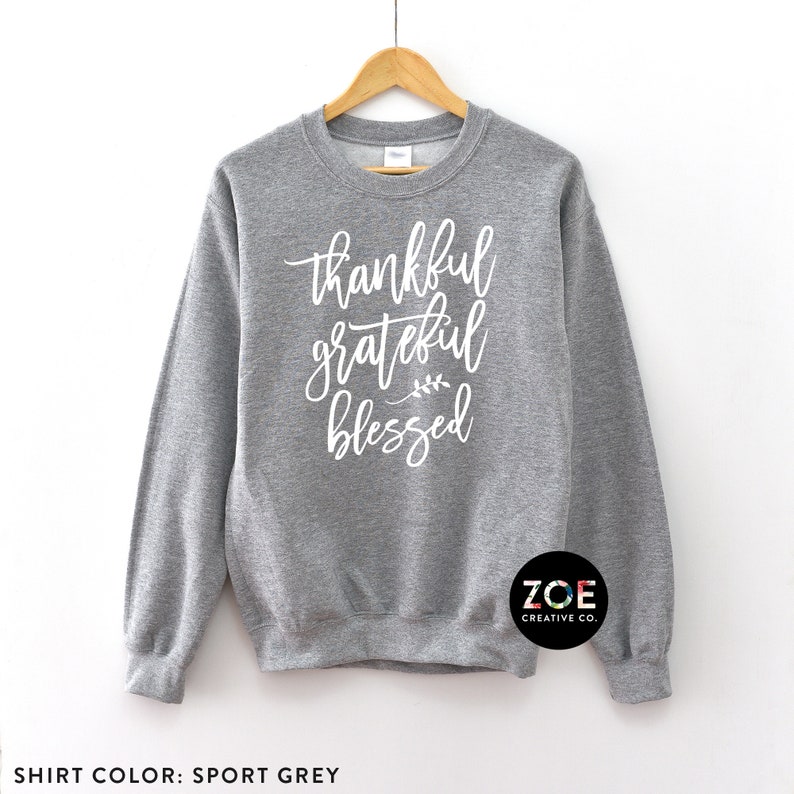 May include: A grey sweatshirt with the text "thankful grateful blessed" in white lettering. The sweatshirt has a crew neck and long sleeves.