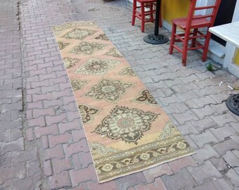 May include: A light pink and beige runner rug with a floral pattern. The rug is laid out on a brick patio.