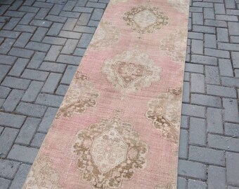 May include: A long, rectangular pink and beige rug with a floral pattern. The rug has a distressed look and is made of a soft, woven material.