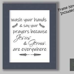 Könnte beinhalten: Ein weißer gerahmter Druck mit schwarzem Text, der "Wasche deine Hände und bete, denn Jesus und Keime sind überall" lautet. Der Rahmen ist dunkelblau und der Text ist in einer handschriftlichen Schrift.