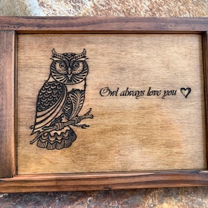 Könnte beinhalten: Eine Holzkiste mit einem dunkelbraunen Rahmen und einem hellbraunen Innenraum. Die Kiste hat ein eingebranntes Bild eines Eulen mit dem Text "Owl always love you" und einem Herzen.
