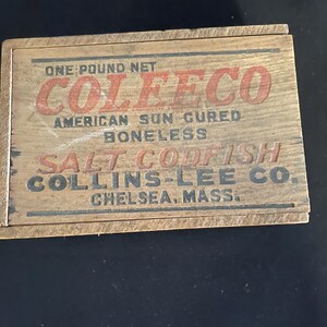 May include: A weathered wooden box with the text "COLEECO" in red, "AMERICAN SUN CURED BONELESS SALT CODFISH" in black, and "ONE POUND NET" at the top. The box is from Collins-Lee Co., Chelsea, Mass.