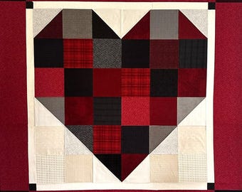 May include: A patchwork quilt with a heart motif. The heart is made from squares and triangles in shades of red, black, grey, and white. The quilt has a red border with black corner squares and a white inner border.