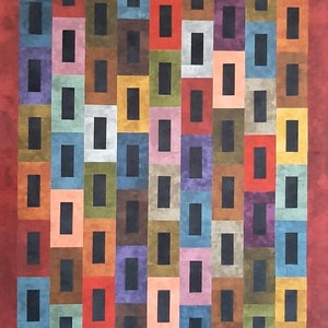 May include: A colorful quilt with a geometric pattern of squares and rectangles. The quilt is made up of different shades of brown, red, blue, green, yellow, and orange. The squares and rectangles are arranged in a repeating pattern, creating a visually appealing design.