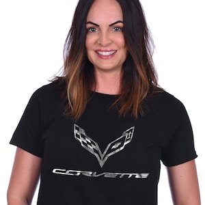 May include: A black t-shirt with a silver Corvette logo and the word "Corvette" printed on the front.