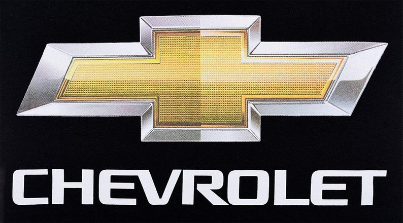 Pode incluir: Um logotipo Chevrolet prateado e dourado com a palavra "CHEVROLET" em letras brancas abaixo.