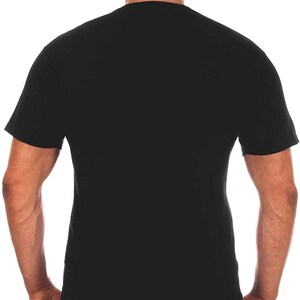 Pode incluir: Uma camiseta preta de manga curta com um bon&eacute; de beisebol preto. A pessoa est&aacute; vestindo jeans azul com costuras prateadas.