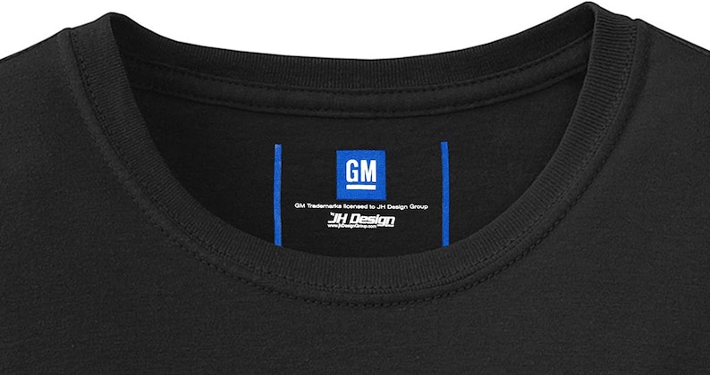 Pode incluir: Uma camiseta preta com uma etiqueta azul que diz "GM Trademarks licensed to JH Design Group" e "JH Design" com um endere&ccedil;o de site.