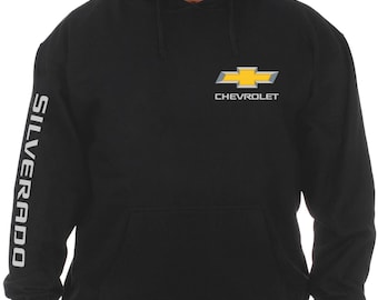 Könnte beinhalten: Schwarzer Kapuzenpullover mit einem weißen "SILVERADO"-Aufdruck auf dem linken Ärmel und einem gelben und silbernen Chevrolet-Logo auf der Vorderseite. Der Text "CHEVROLET" ist unter dem Logo gedruckt.