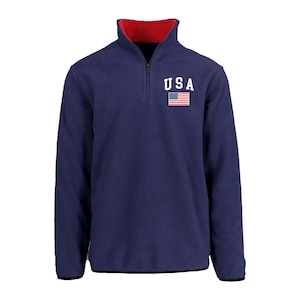 May include: Navy blue fleece pullover with a red collar and a quarter-zip closure. The chest features the word "USA" in white block letters above a small American flag. The cuffs and hem are black.