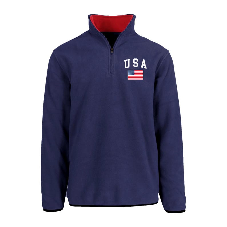 May include: Navy blue fleece pullover with a red collar and a quarter-zip closure. The chest features the word "USA" in white block letters above a small American flag. The cuffs and hem are black.