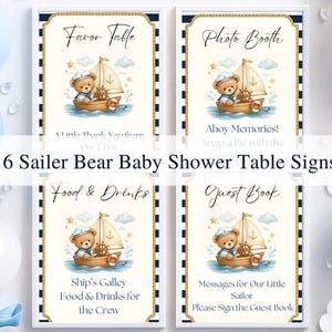 May include: Set of six baby shower table signs with a nautical theme. Each sign features a teddy bear sailor in a boat, with text such as "Favor Table" and "Photo Booth". The signs have a navy blue and gold border.