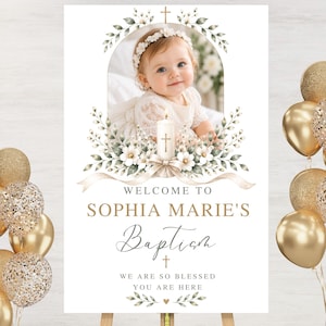 Pode incluir: Uma placa retangular de boas-vindas para batizado com a foto de um bebé com vestido branco e fita floral. O design inclui uma ilustração central de uma vela, folhagem verde e o texto: WELCOME TO SOPHIA MARIE'S Baptism WE ARE SO BLESSED YOU ARE HERE.