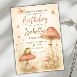 May include: A whimsical invitation with a watercolor design. The text reads "Join us for an Enchanted Birthday to Celebrate Isabella's 7th Birthday." The design includes mushrooms, butterflies, a frog, and floral elements. The invitation is in soft pastel colors.