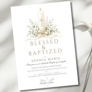 Puede incluir: Una tarjeta de invitación de bautizo blanca con una ilustración en acuarela de una vela encendida con una cruz dorada, rodeada de follaje verde y una cinta color crema. El texto dice BLESSED & BAPTIZED, SOPHIA MARIE y los detalles del evento.