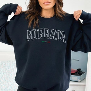May include: A navy blue sweatshirt with the word "BURRATA" printed in white with a white outline. The Italian flag is printed below the word in red, white, and green.