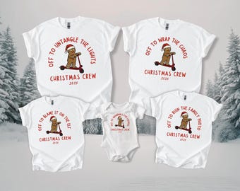 May include: White t-shirts and a onesie with Christmas-themed graphics. Each shirt features a gingerbread man on a scooter with phrases like "Off to Untangle the Lights" and "Christmas Crew 2025".