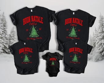 May include: Black t-shirts and a onesie with a Christmas tree design. The text on the shirts reads "BUON NATALE CREW" in red, with the year "20" and "26" and "The Rose Family" in green.