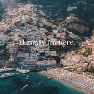 Peut inclure: Vue a&eacute;rienne d'une ville c&ocirc;ti&egrave;re avec des b&acirc;timents color&eacute;s construits &agrave; flanc de colline. La ville est situ&eacute;e sur une p&eacute;ninsule avec une plage et une eau bleu clair. Le texte "Mentally I'm here." est superpos&eacute; &agrave; l'image.