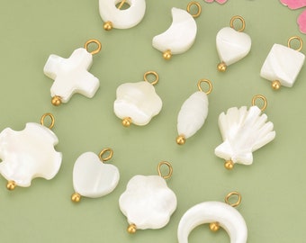May include: A set of 12 white mother of pearl charms with gold accents. The charms are in various shapes, including a cross, a heart, a flower, a crescent moon, and a seashell.