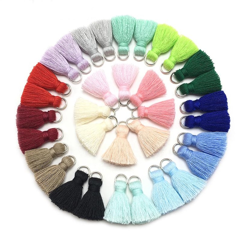 May include: Assortment of 20 colorful tassel trims with silver rings. The tassels are made of soft yarn and come in a variety of colors, including red, blue, green, pink, and white.