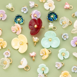 Puede incluir: Surtido de abalorios de flores de colores con detalles dorados. Los abalorios están hechos de varios materiales, como plástico, vidrio y metal. Son perfectos para añadir un toque de fantasía a las joyas, las manualidades y otros proyectos.