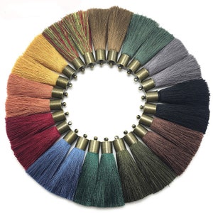 Puede incluir: Un conjunto de 18 borlas de colores con tapas de metal dorado. Las borlas están dispuestas en círculo, con las tapas doradas hacia afuera. Las borlas están hechas de un material suave y sedoso y son perfectas para agregar un toque de elegancia a cualquier proyecto.