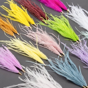 May include: Assortment of colourful ostrich feather boas in various colours, including yellow, pink, green, white, and purple. The feathers are arranged in a fan shape and have a soft, fluffy texture.