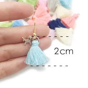 May include: Light blue tassel earrings with a gold dog charm. The tassel is 2 cm long.