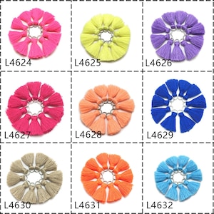May include: Assortment of 12 colorful tassel keychains, each keychain features a circle of 10 tassels with a silver ring. The keychains are arranged in a grid of 3 rows and 4 columns. The colors are: pink, yellow, purple, red, orange, blue, beige, coral, and light blue. Each keychain is labeled with a product code: L4624, L4625, L4626, L4627, L4628, L4629, L4630, L4631, and L4632.