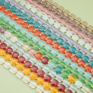 Può includere: File di perline colorate e sfaccettate in vari colori, tra cui rosso, arancione, verde, blu e viola. Le perline sono infilate con connettori color oro, creando un motivo vibrante e accattivante. Le perline sono disposte in file diagonali.