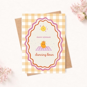 May include: A greeting card with a brown envelope. The card has a gingham pattern in yellow and white. The card features a dancing bean character with the words "Happy Birthday" and "dancing bean".