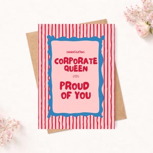 May include: A rectangular greeting card featuring a pink background with red vertical stripes. A central light pink rectangle with a blue wavy border contains the red text: CONGRATULATIONS CORPORATE QUEEN PROUD OF YOU, with a small heart icon.