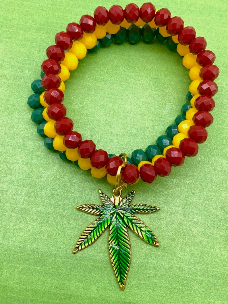 May include: A red, yellow, and green beaded bracelet with a gold marijuana leaf charm.