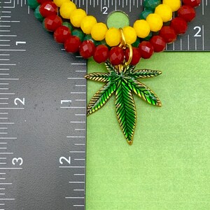 May include: Three-strand beaded bracelet with red, green, and yellow beads. The bracelet has a gold-tone marijuana leaf charm.